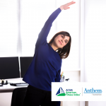 woman standing and stretching at her desk