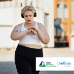 woman wearing headphones, walking and checking an activity tracker on her wrist
